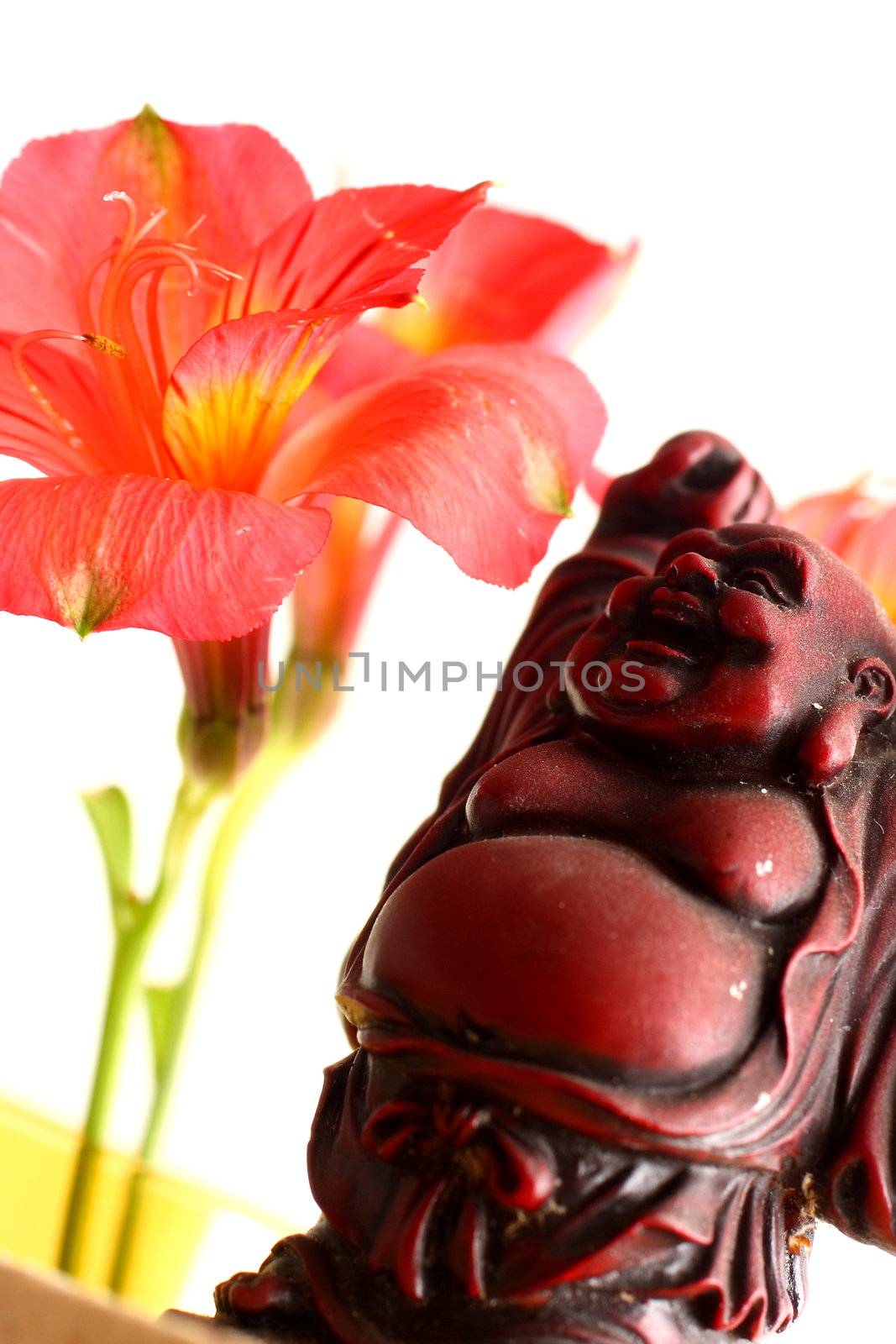 Red Buddha statue with red Peruvian lilies