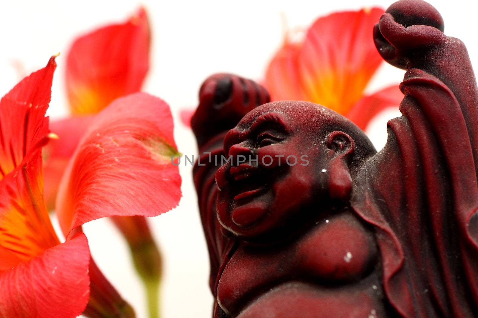 Red Buddha statue with red Peruvian lilies
