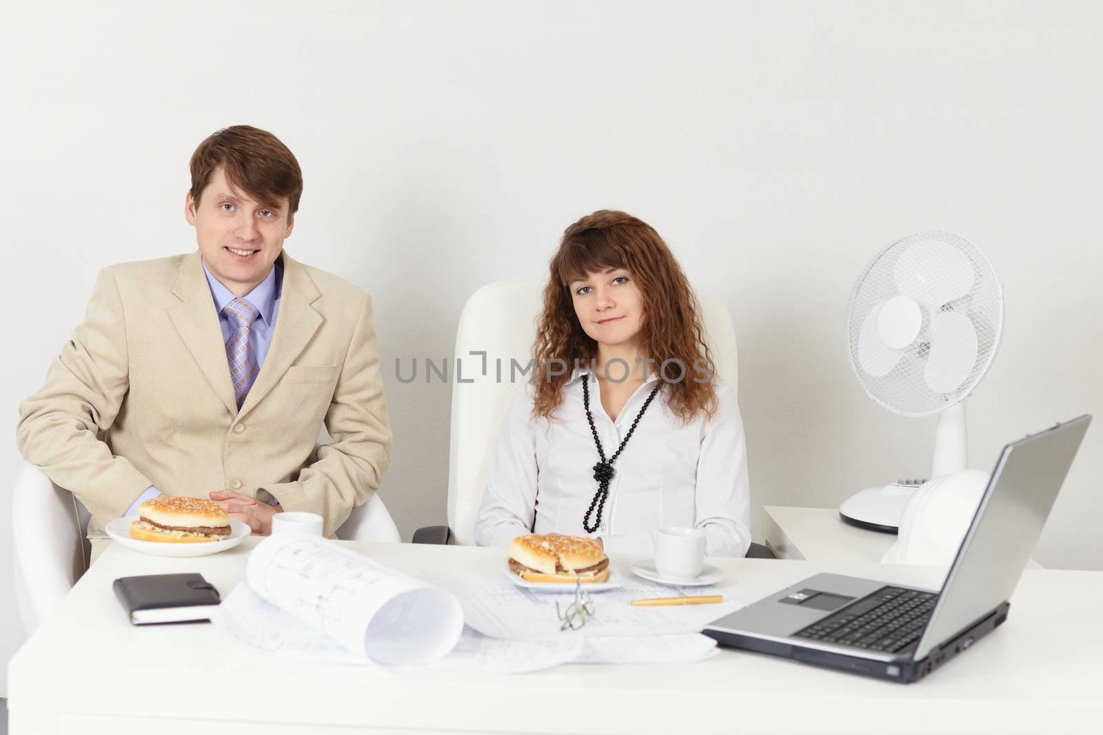 Business people - a man and woman meet for dinner at the workplace in the office
