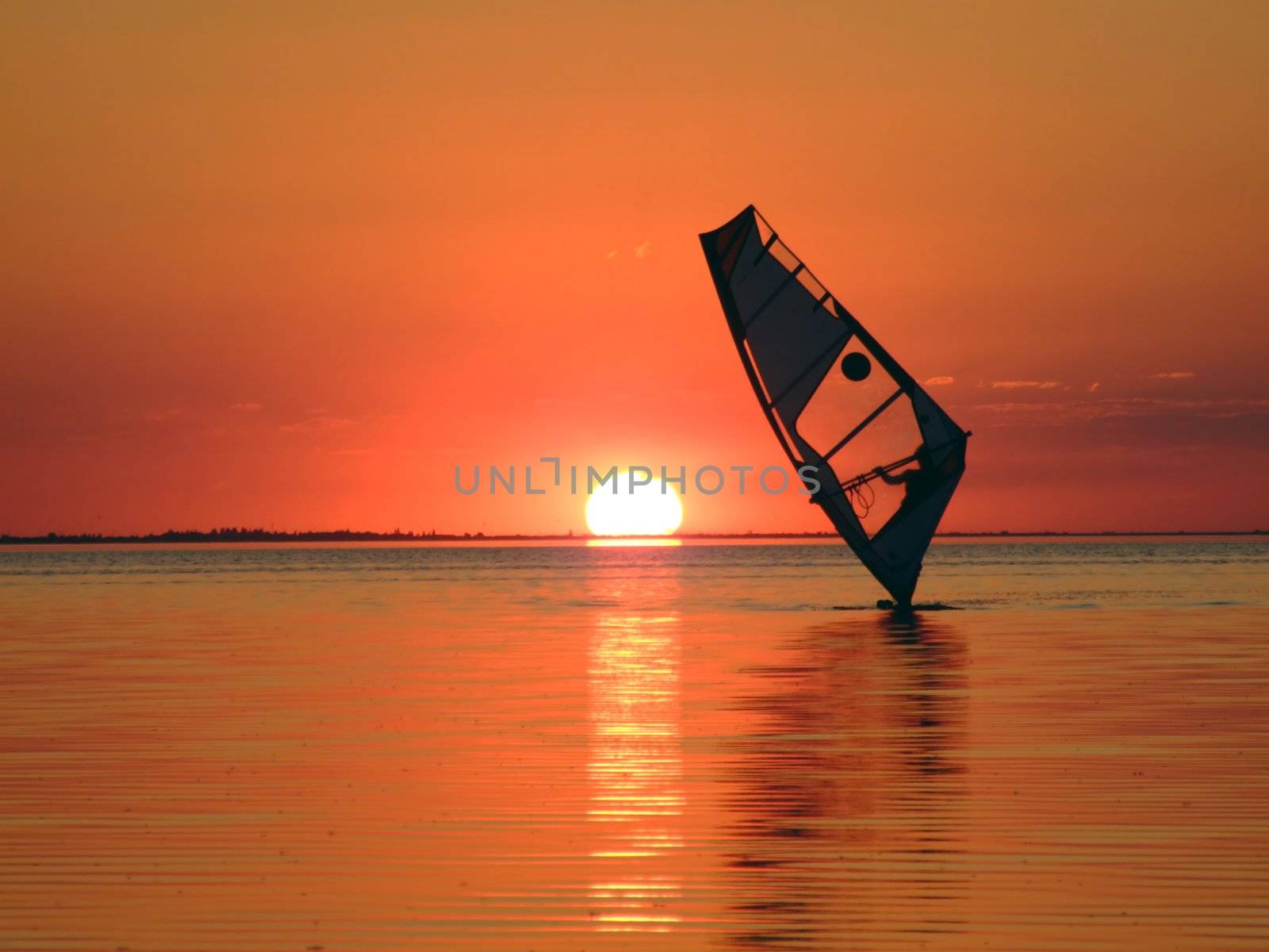 Silhouette of a windsurfer on waves of a gulf on a sunset 1