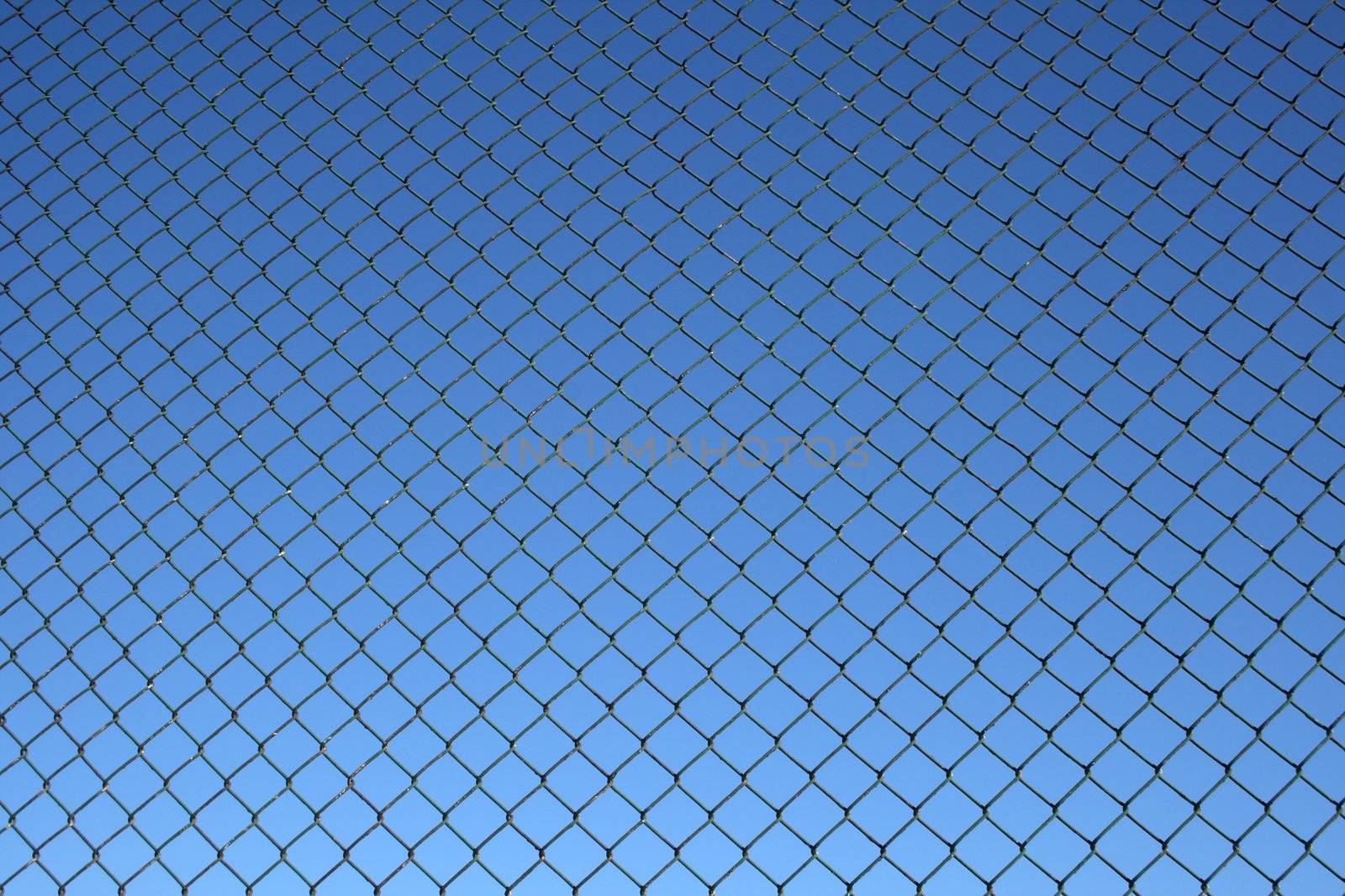 Chain link fence, a bit old and rusty, on a blue sky background.