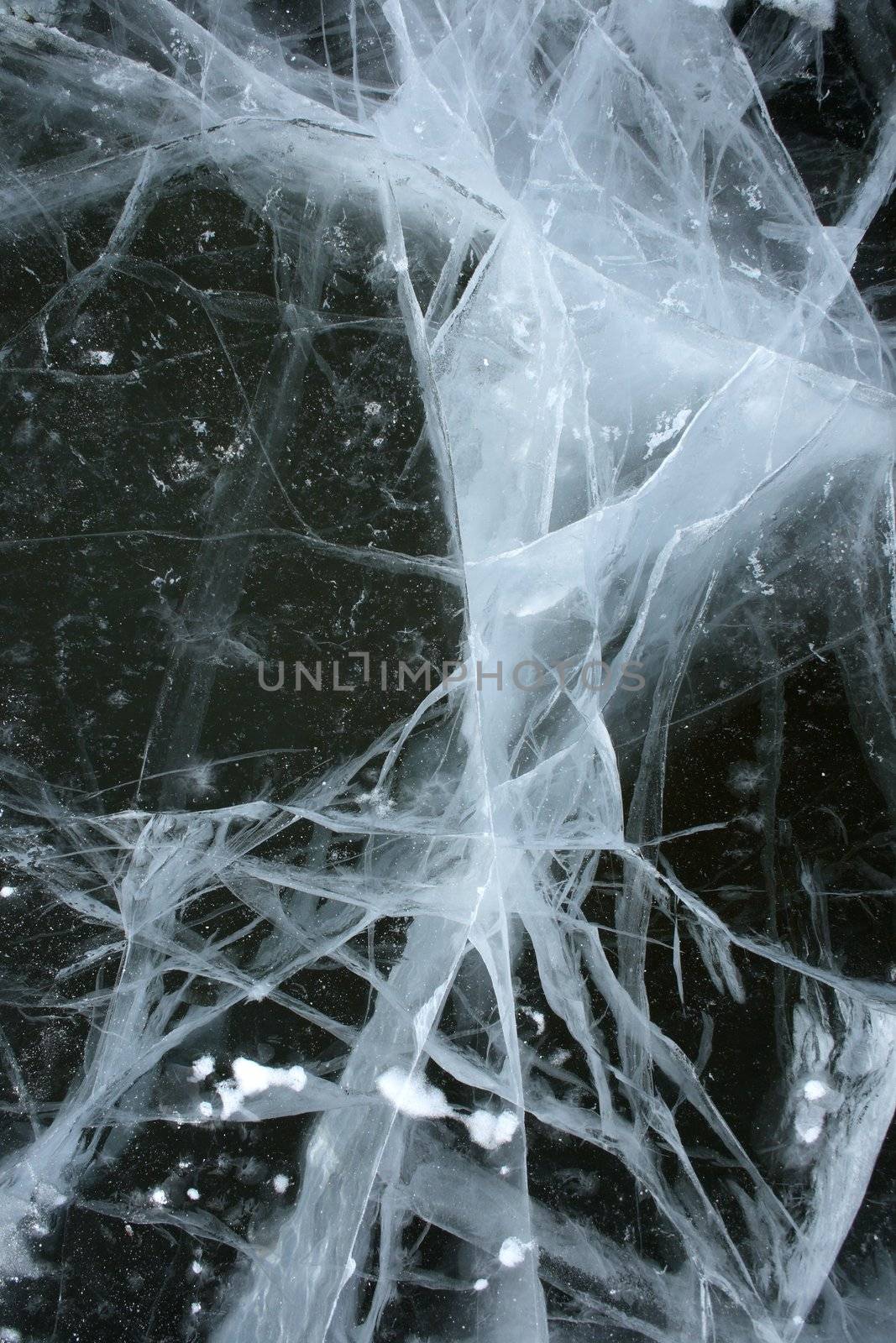 Black water of a frozen river and spooky cracked ice reminding abstract x-ray scan.