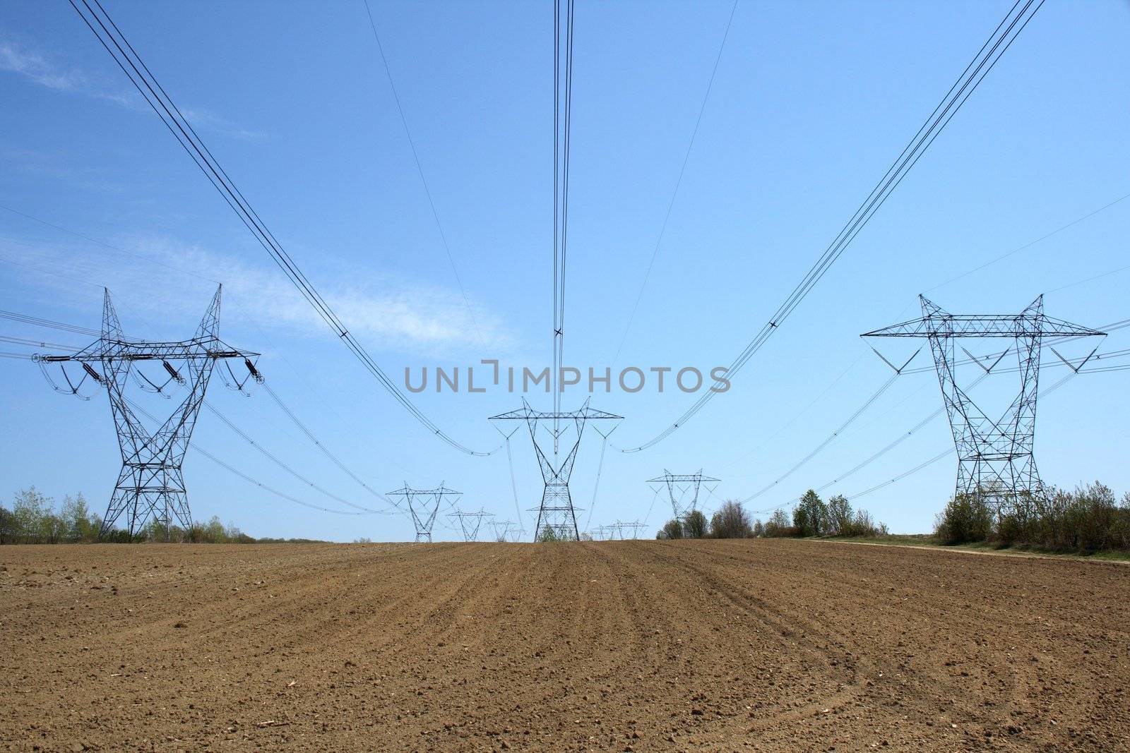 Nature and technology. Ploughed land ready for cultivation and electricity pylons.