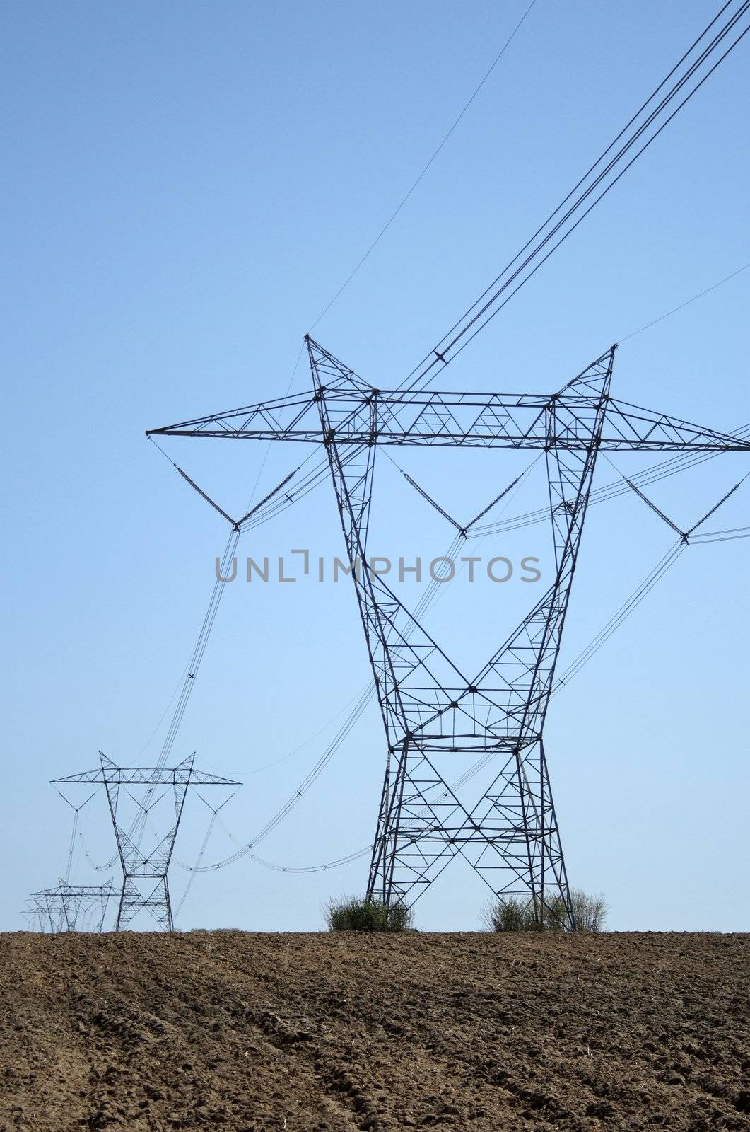 Electricity pylons in ploughed farmland in spring.