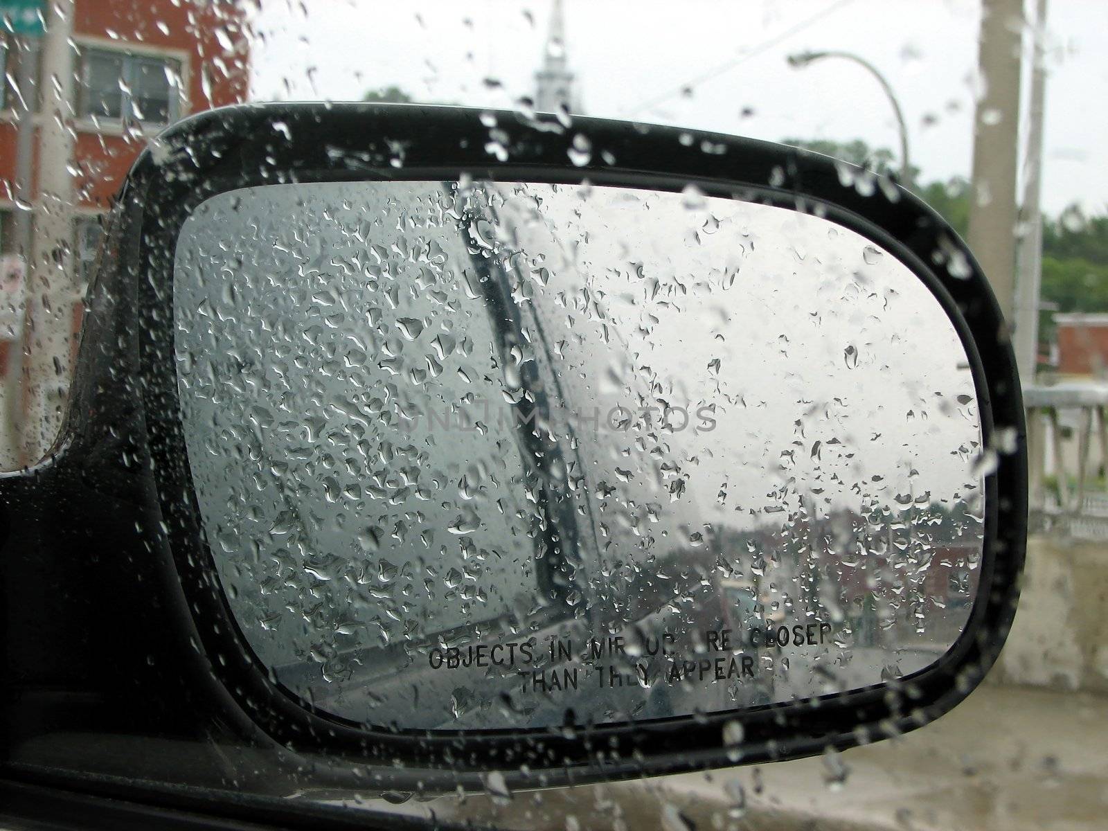 Rainy day: raindrops on a car window and rear mirror.