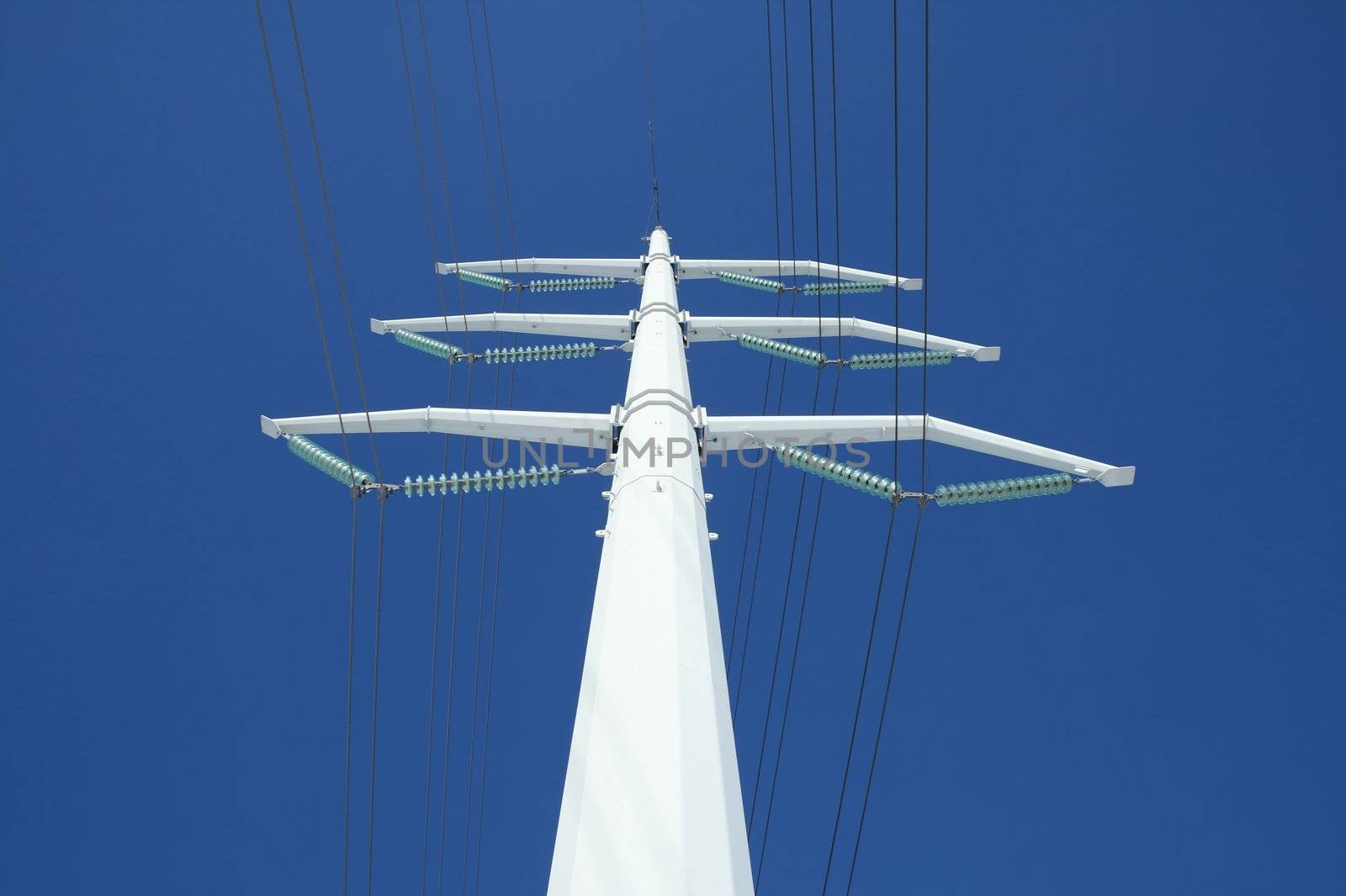 White high voltage electricity pylon against the deep blue sky, from below.