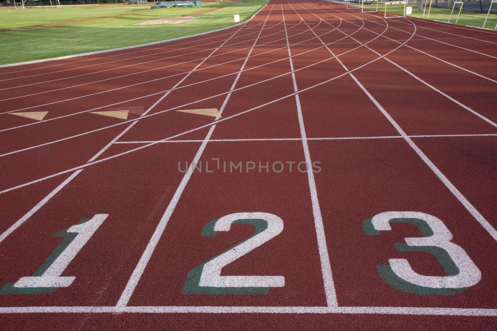 red running track with 1, 2, 3 numbers at the starting line and  green fields