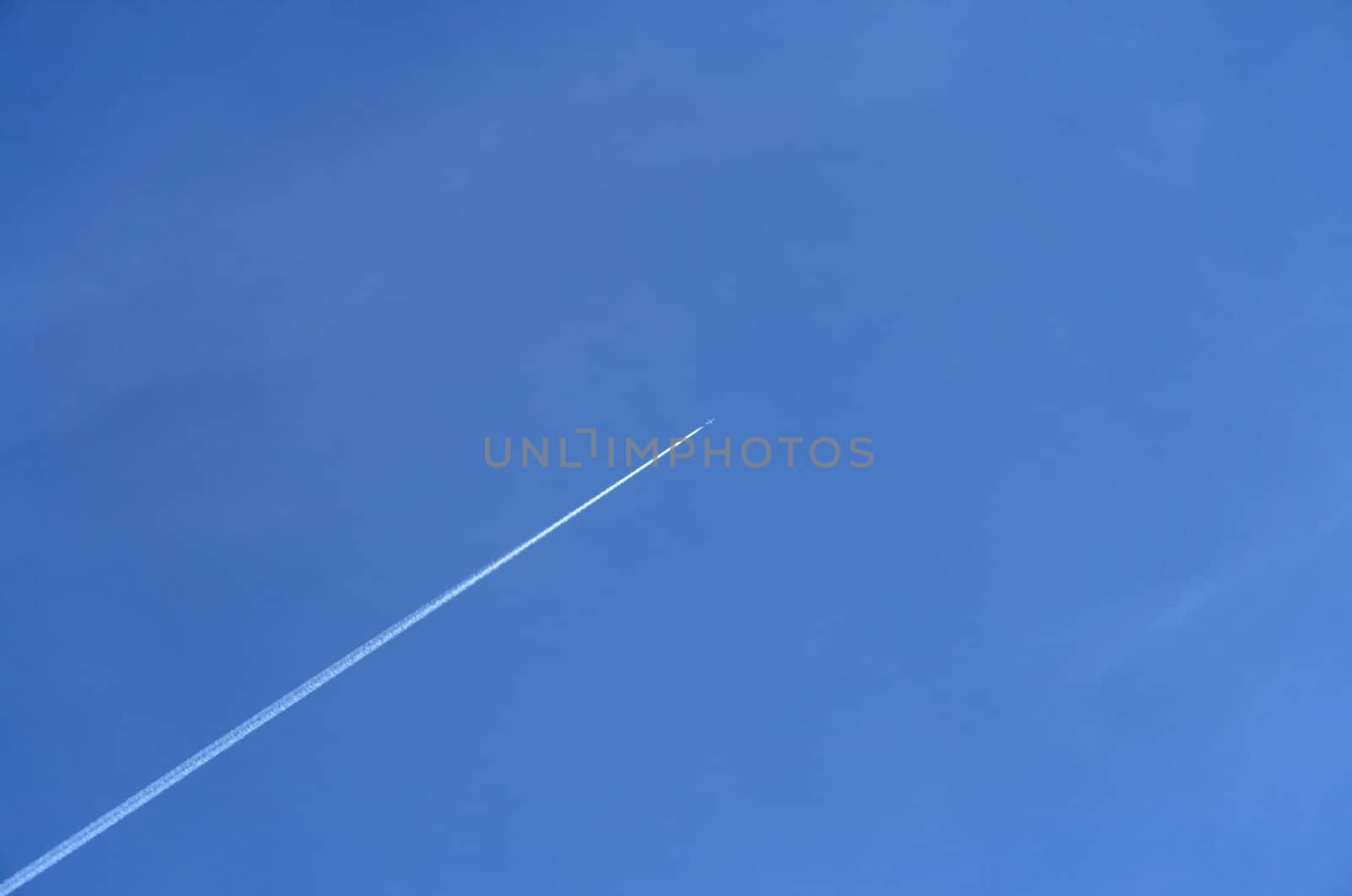 Trace of a jet airplane going up in the blue sky.