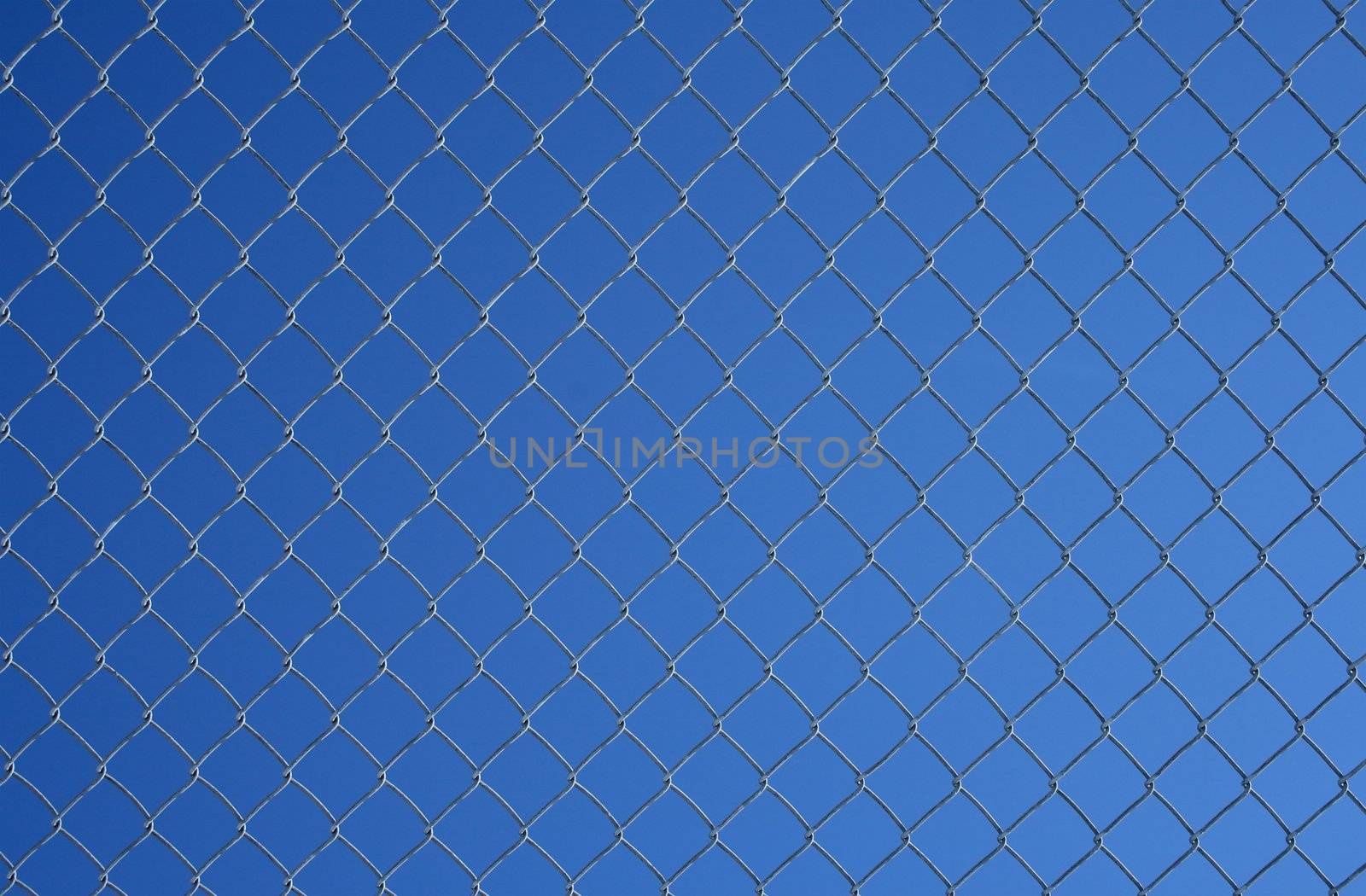 Gray chain link fence on a blue sky background.