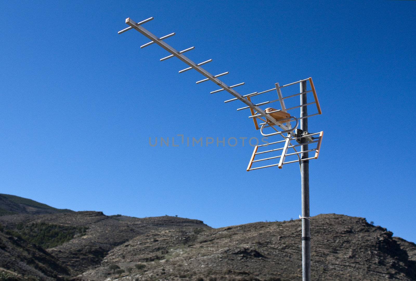 TV aerial with mountains and blue sky as background.