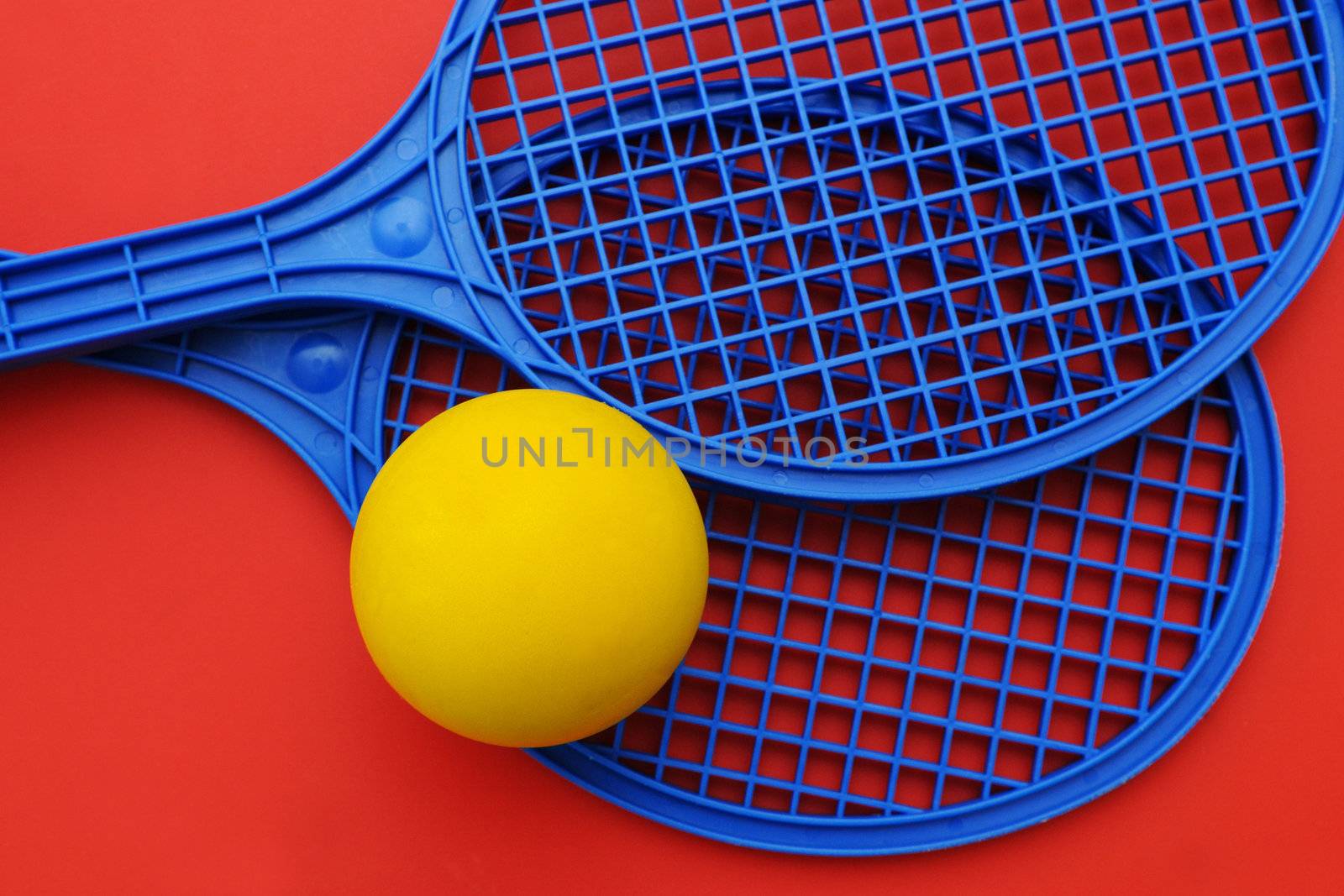 Two toy rackets and yellow ball
