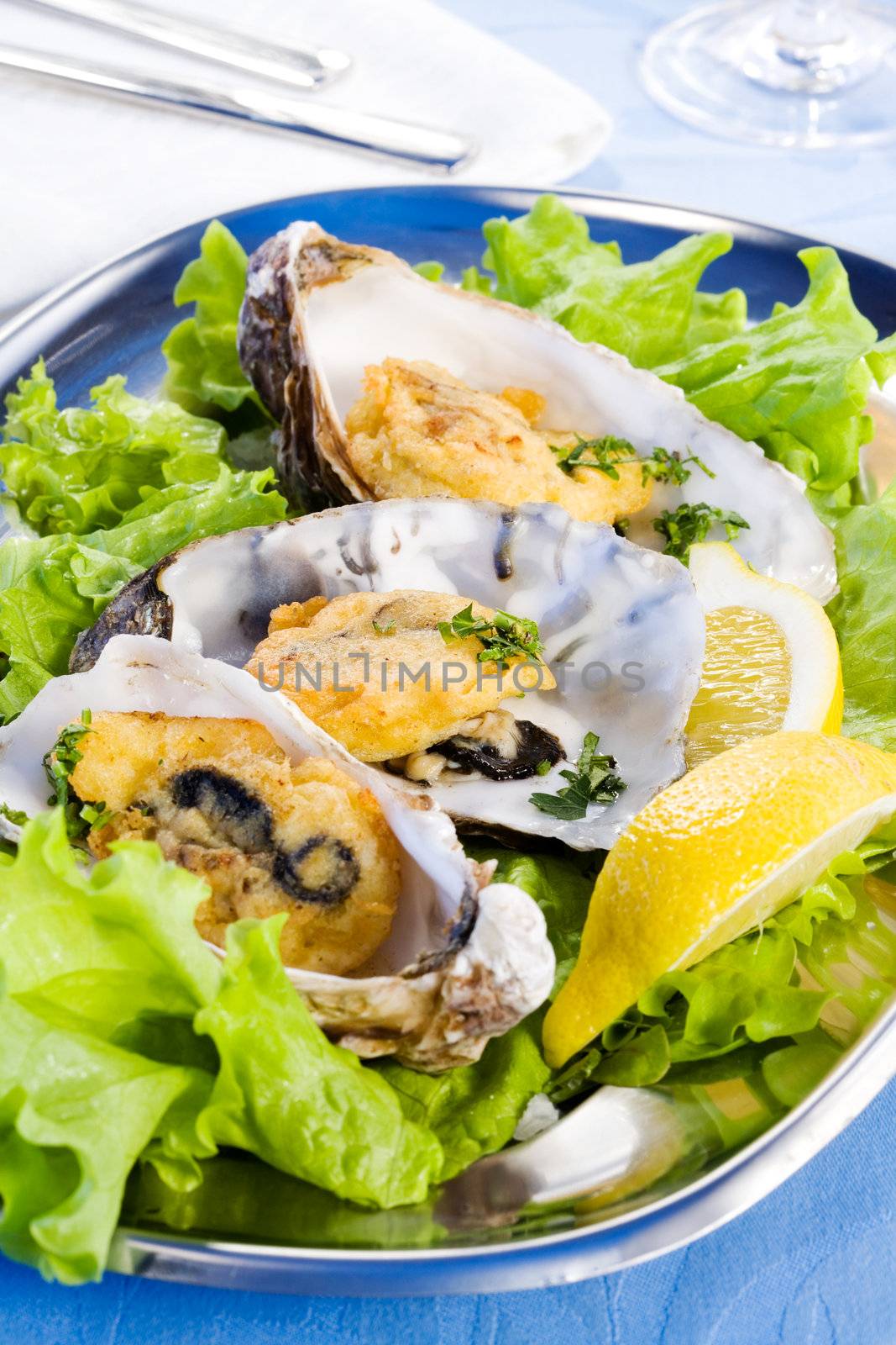 Oysters with lemon, spicery and salad on plate