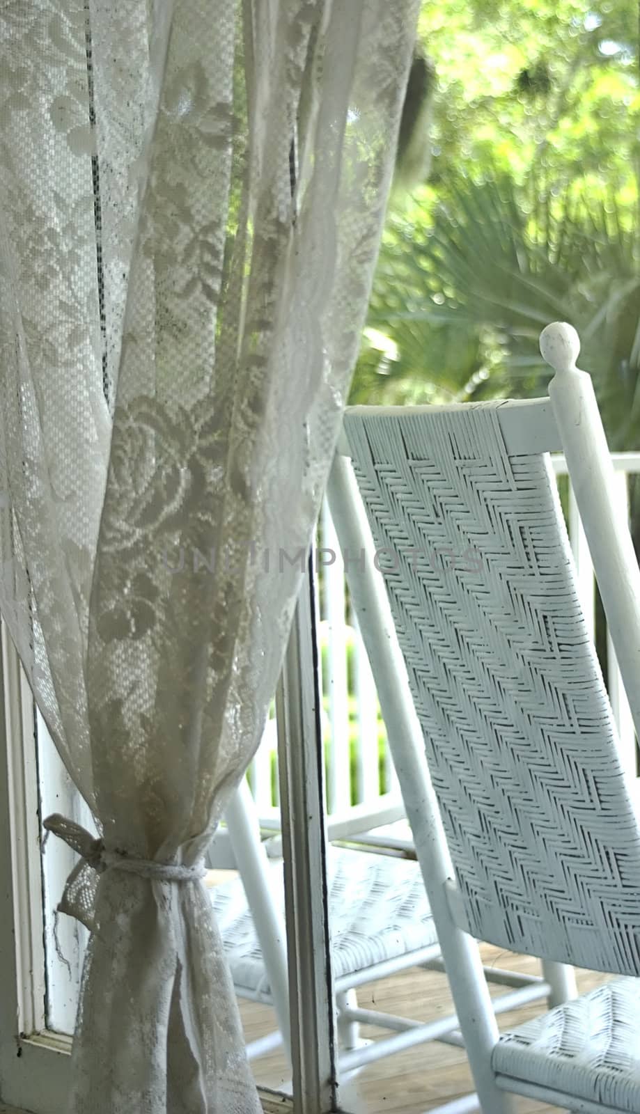 A peaceful image of window lace and rocking chair. 