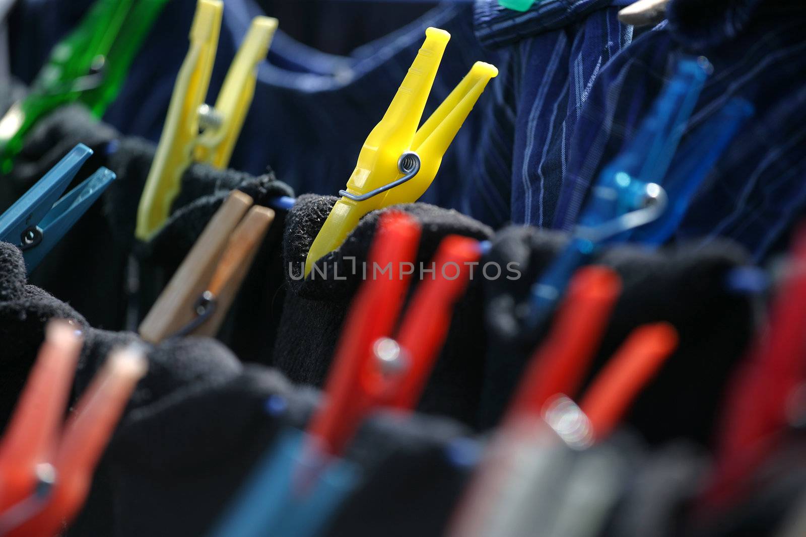 Colourful clothespins hanging dark laundry to dry.
