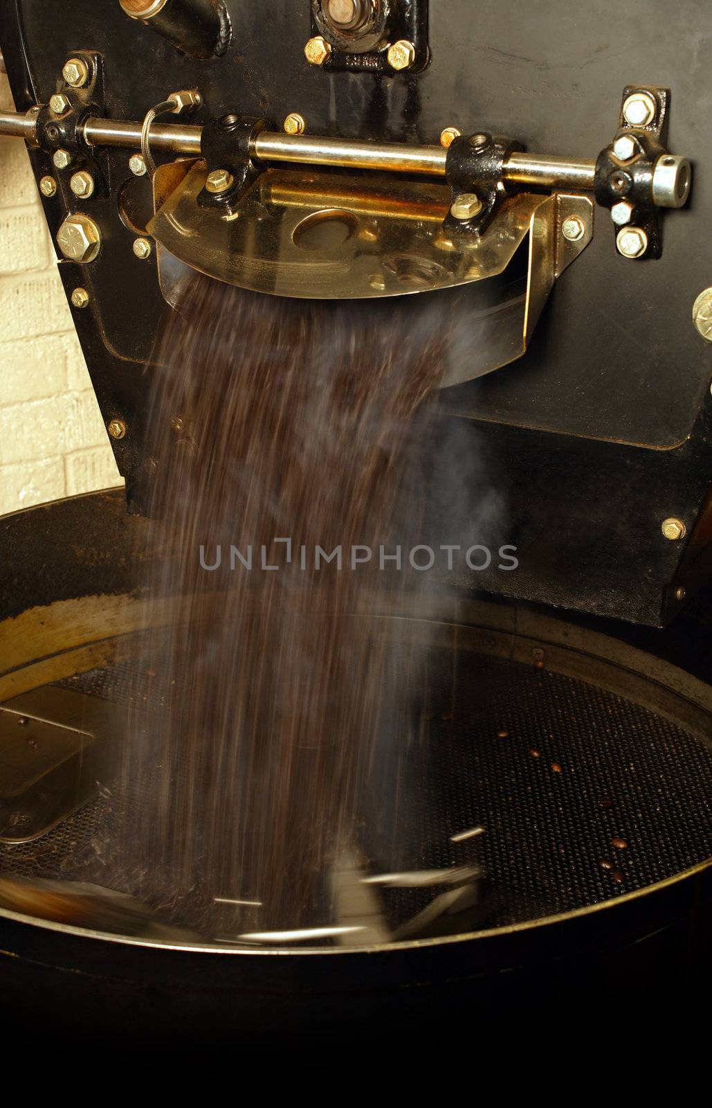 A large coffee roaster, just as the beans are extracted and slowly stirred in the cooling cylinder.
