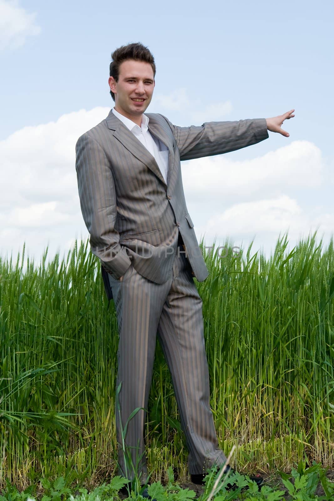Agronomist. Businessman on a green field against the cloudy sky