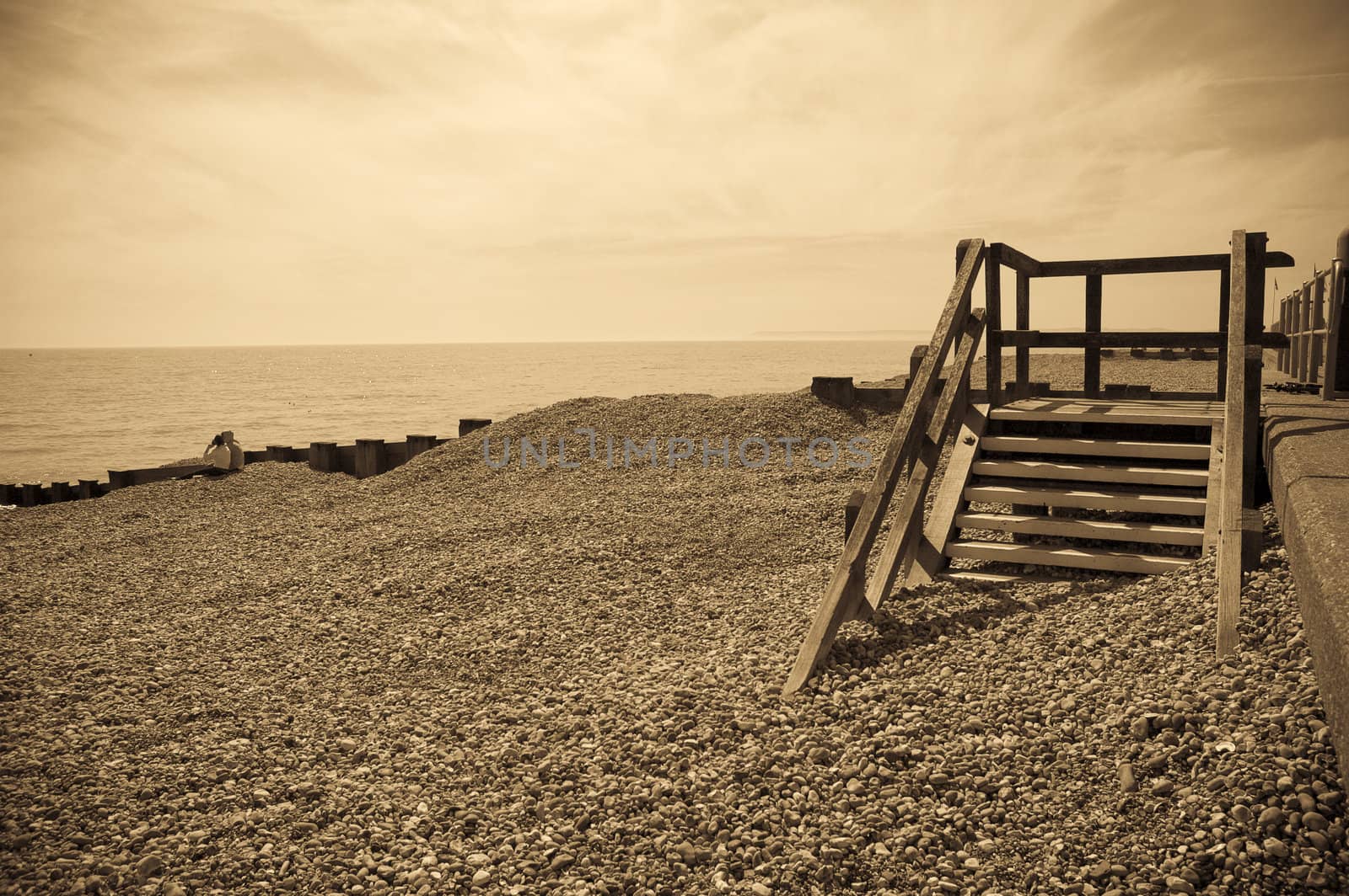 A sepia toned image of a seafront with some old wooden steps