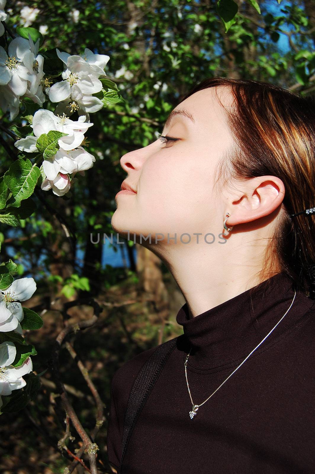 Beautiful girl sniffing blooming appletree
