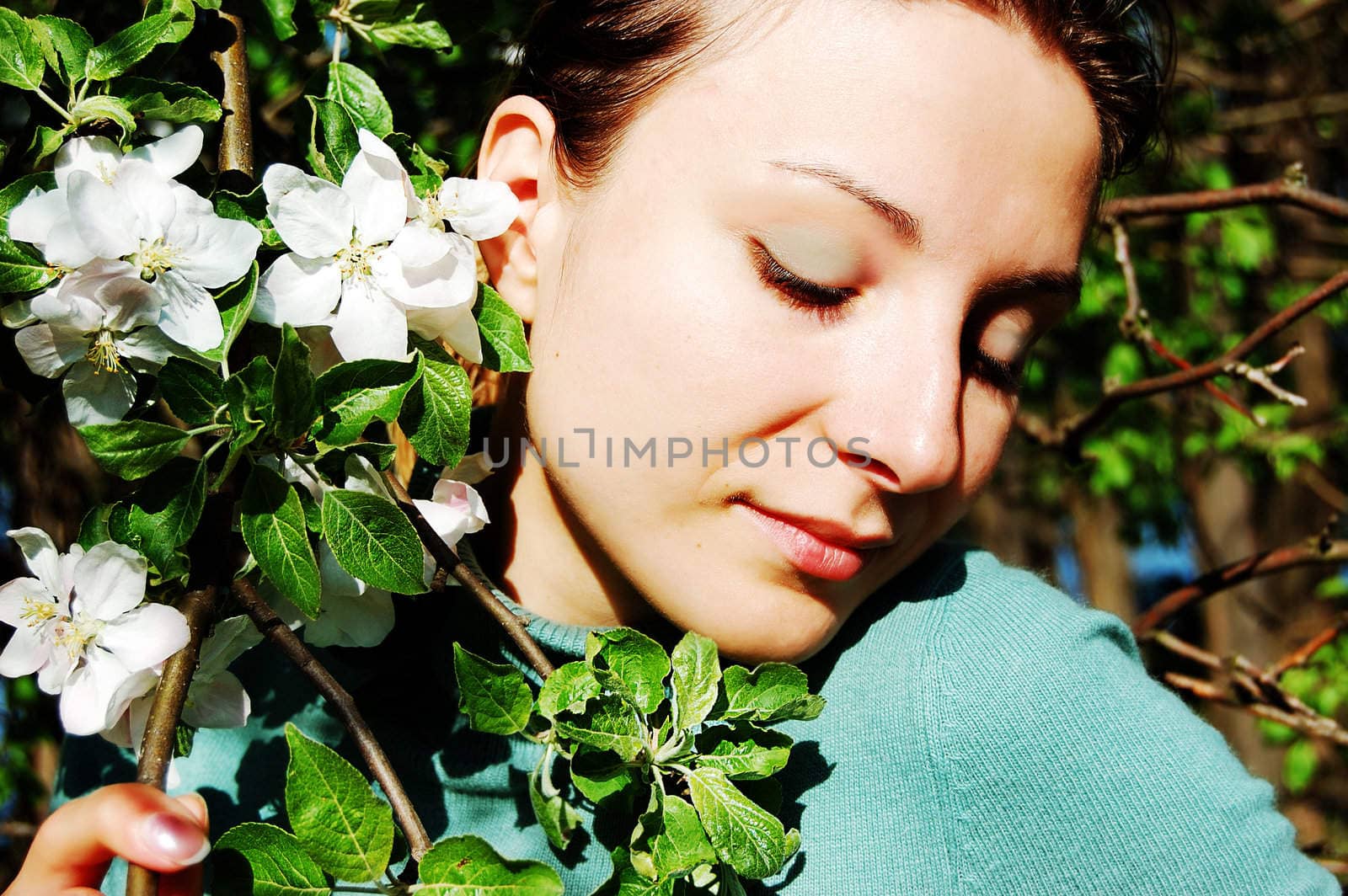 Beautiful girl among blooming appletree