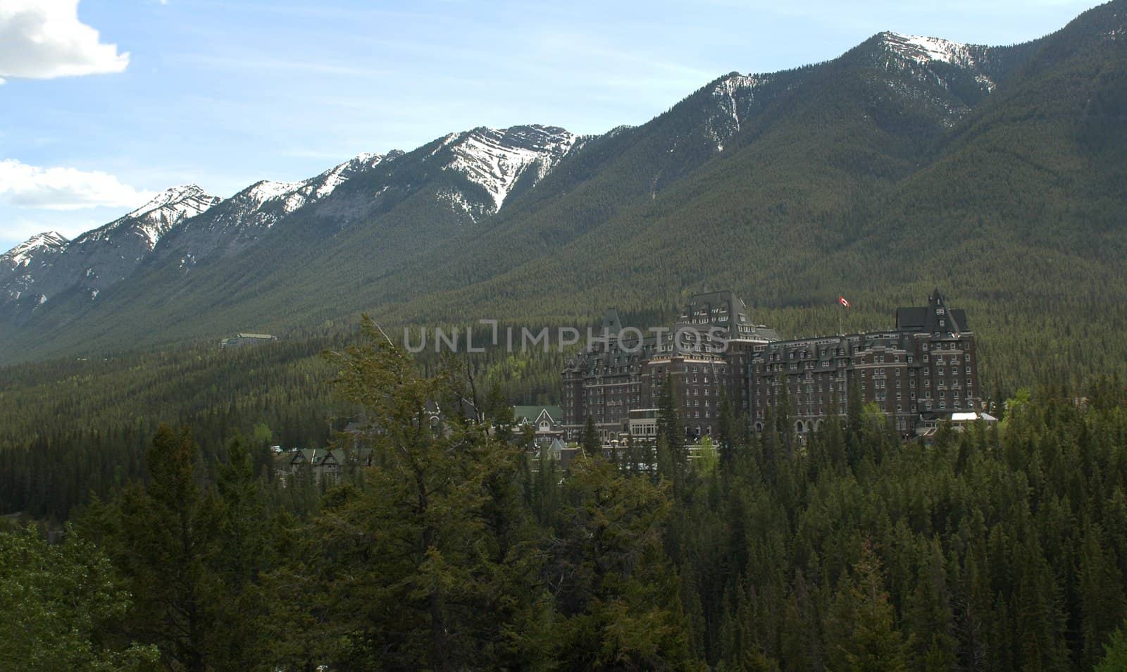 Image of the Fairmont Hotel nestled between mountains and Pine forest in Banf Alberta, Canada.