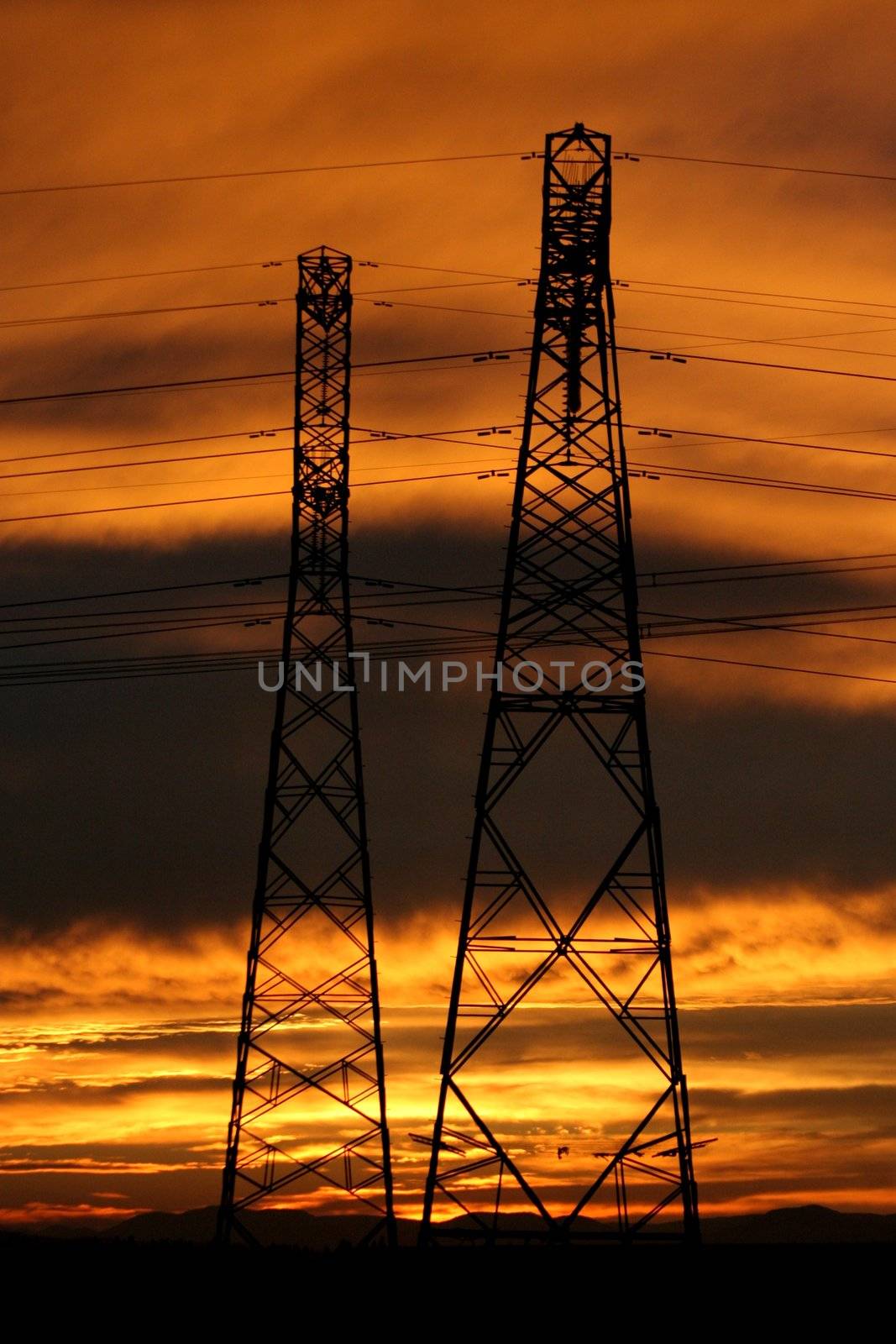 Silhouette of electric pylons with African sunset in background