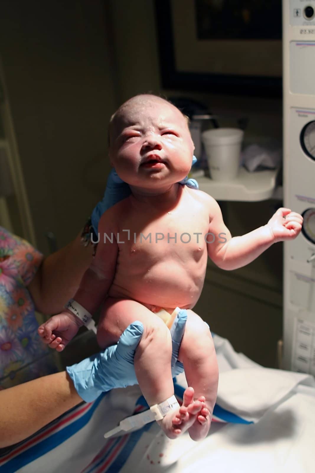 A newborn baby being held up by the nurse