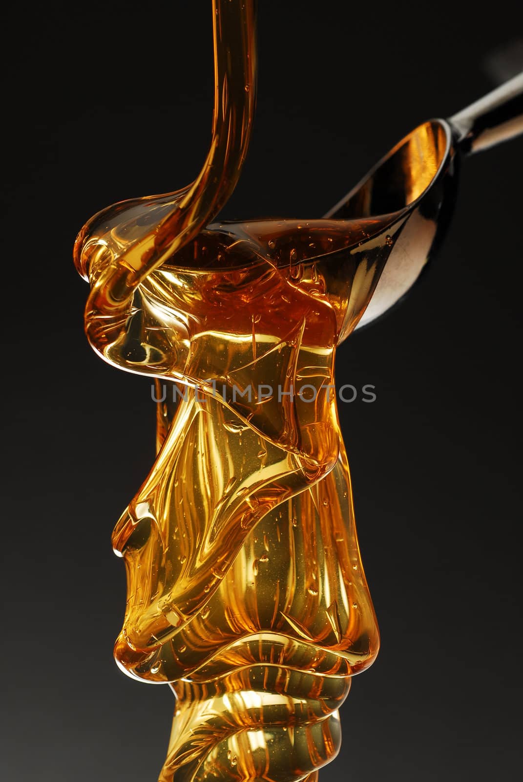 Golden honey dripping from a spoon stock photo