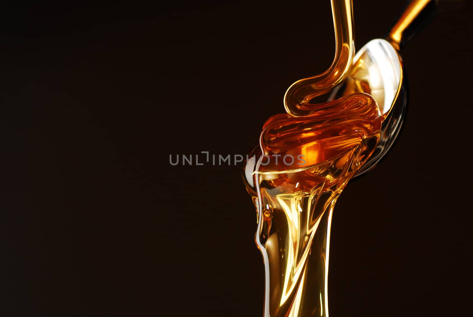 Honey flowing out of the spoon stock photo