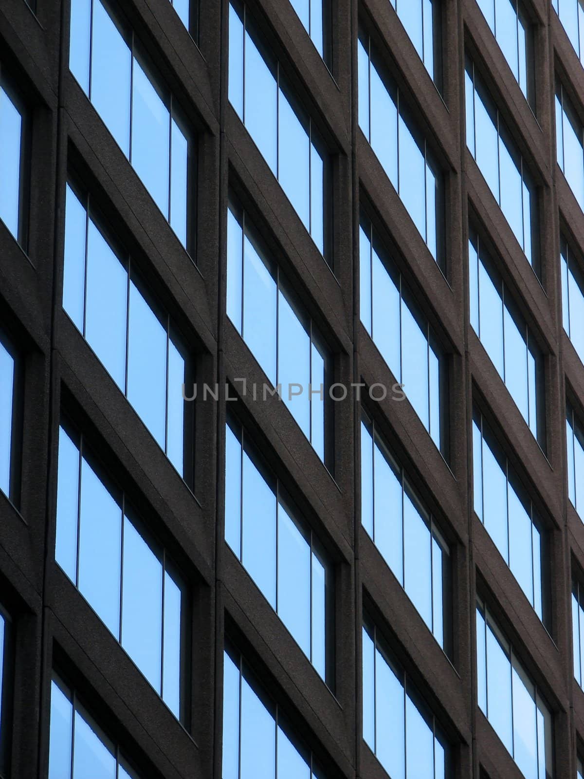 A glass-windowed corporate building reflects the blue sky.