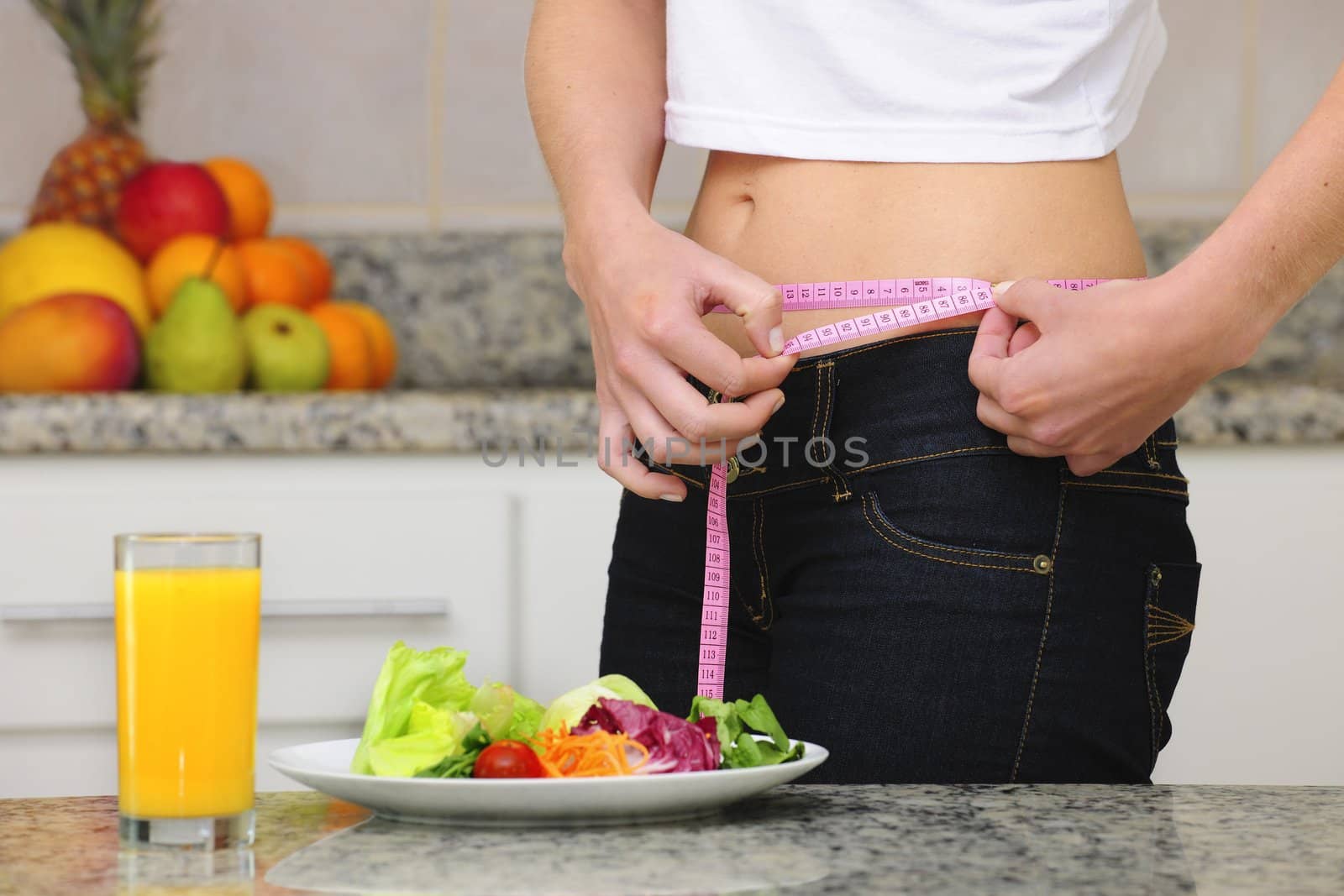 woman eating salad and fruits and measuring her waist