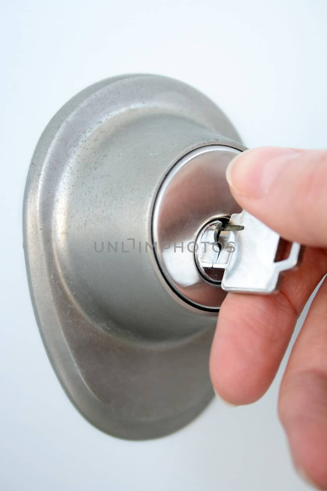 Woman's hand unlocking the door with a key. Focus on the keyhole.
