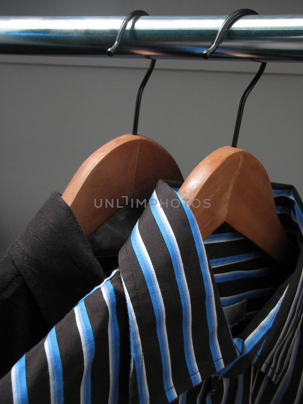 Two stylish shirts on wooden hangers by anikasalsera