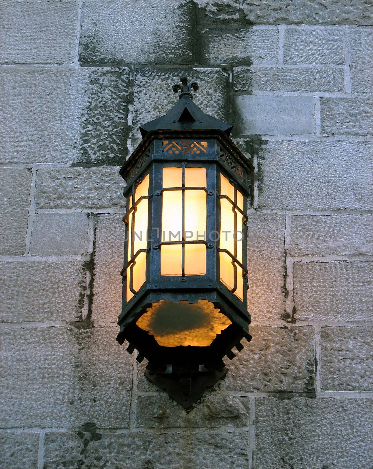 Antique lantern on the wall of an old stone building.
