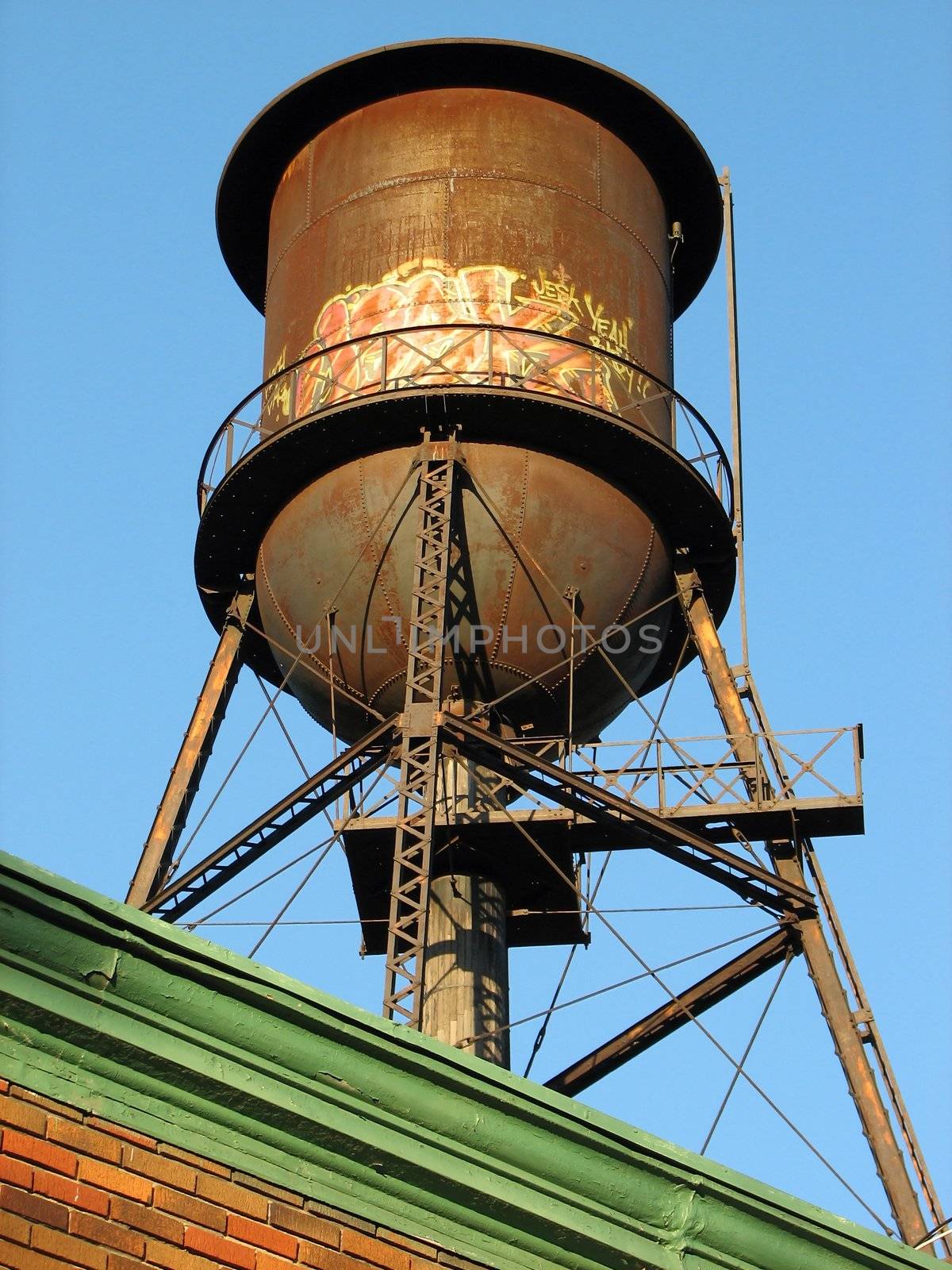 Old rusty water tank on the roof of a brick building.