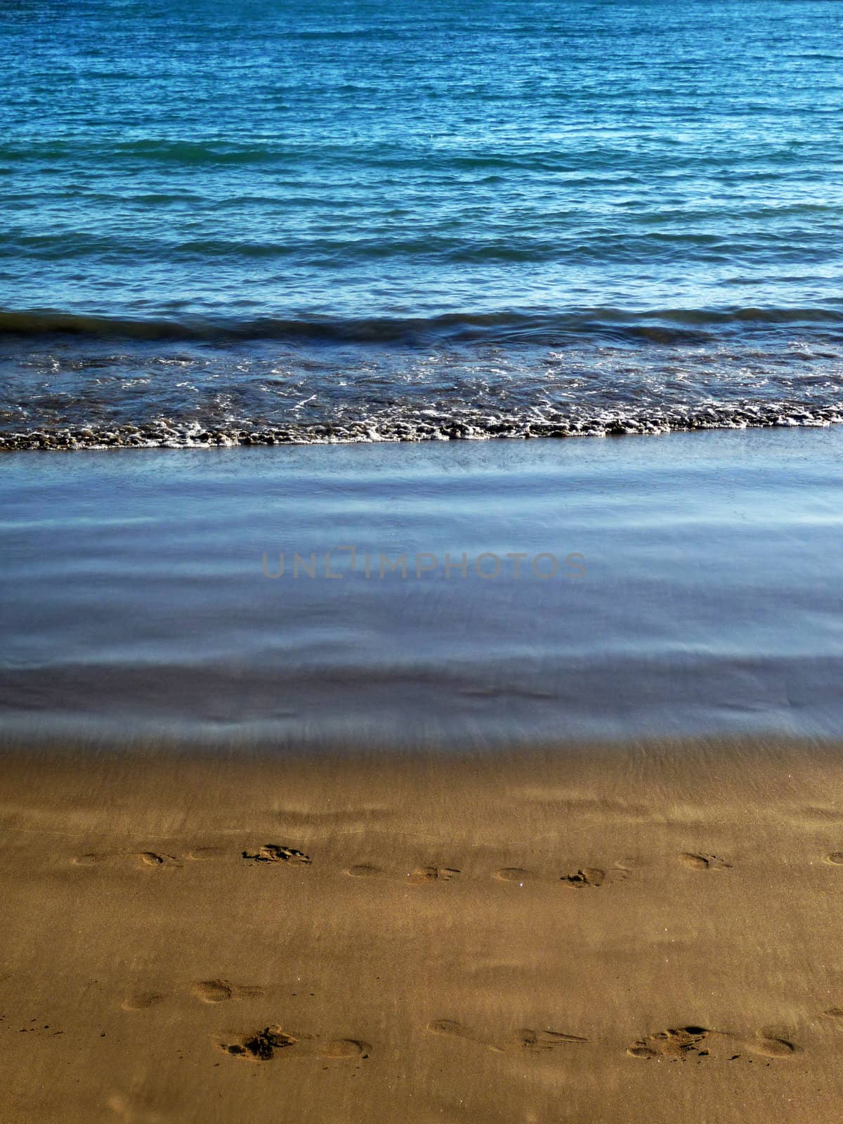 Water waves washing up onto the sandy beach.