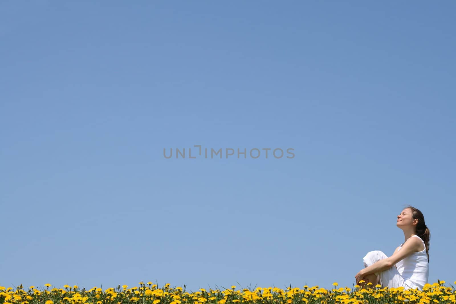 Pretty young woman enjoying sunshine and fresh air in a flowering field.