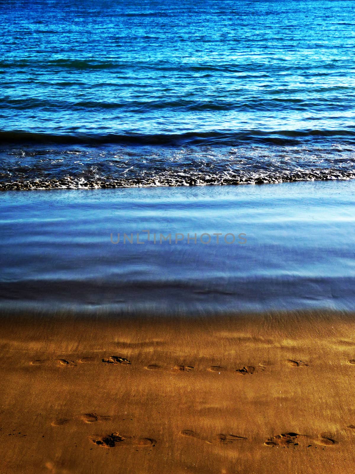 Water waves washing up onto the sandy beach.