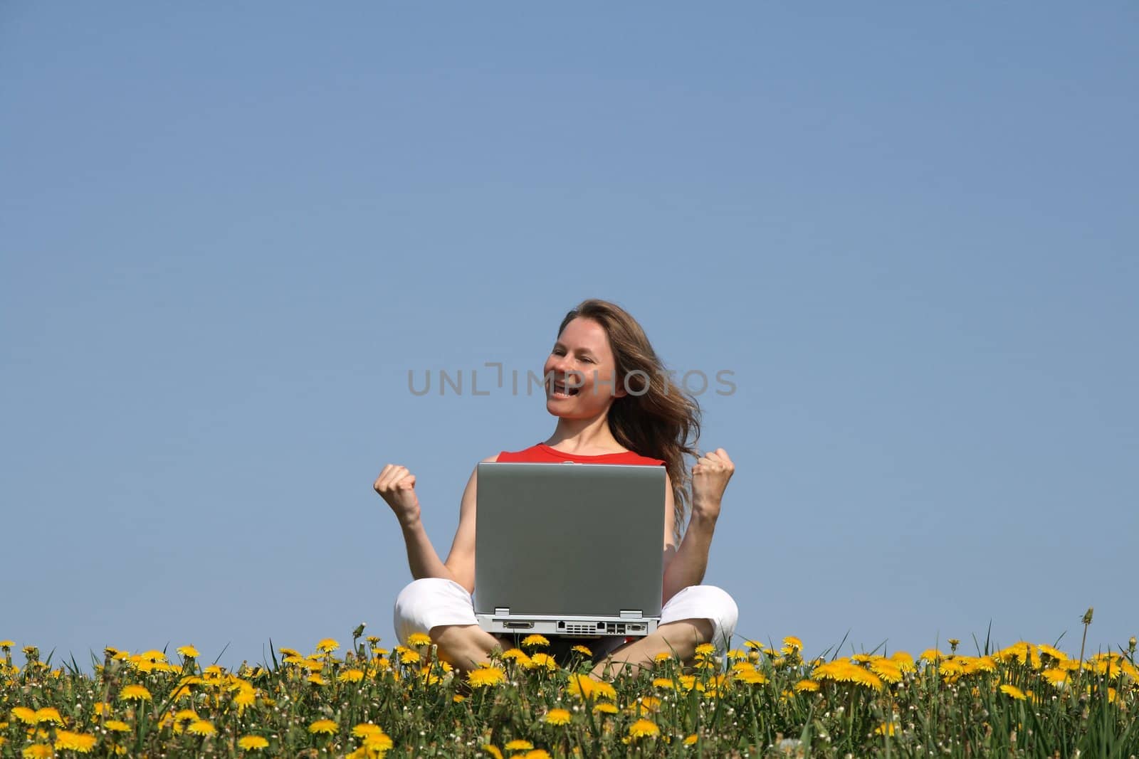 Happy successful woman with laptop in a flowering spring field.