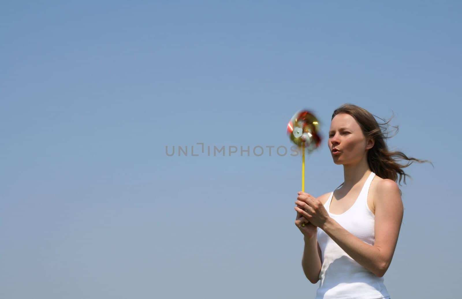 Young woman blowing a colorful pinwheel. Summertime.