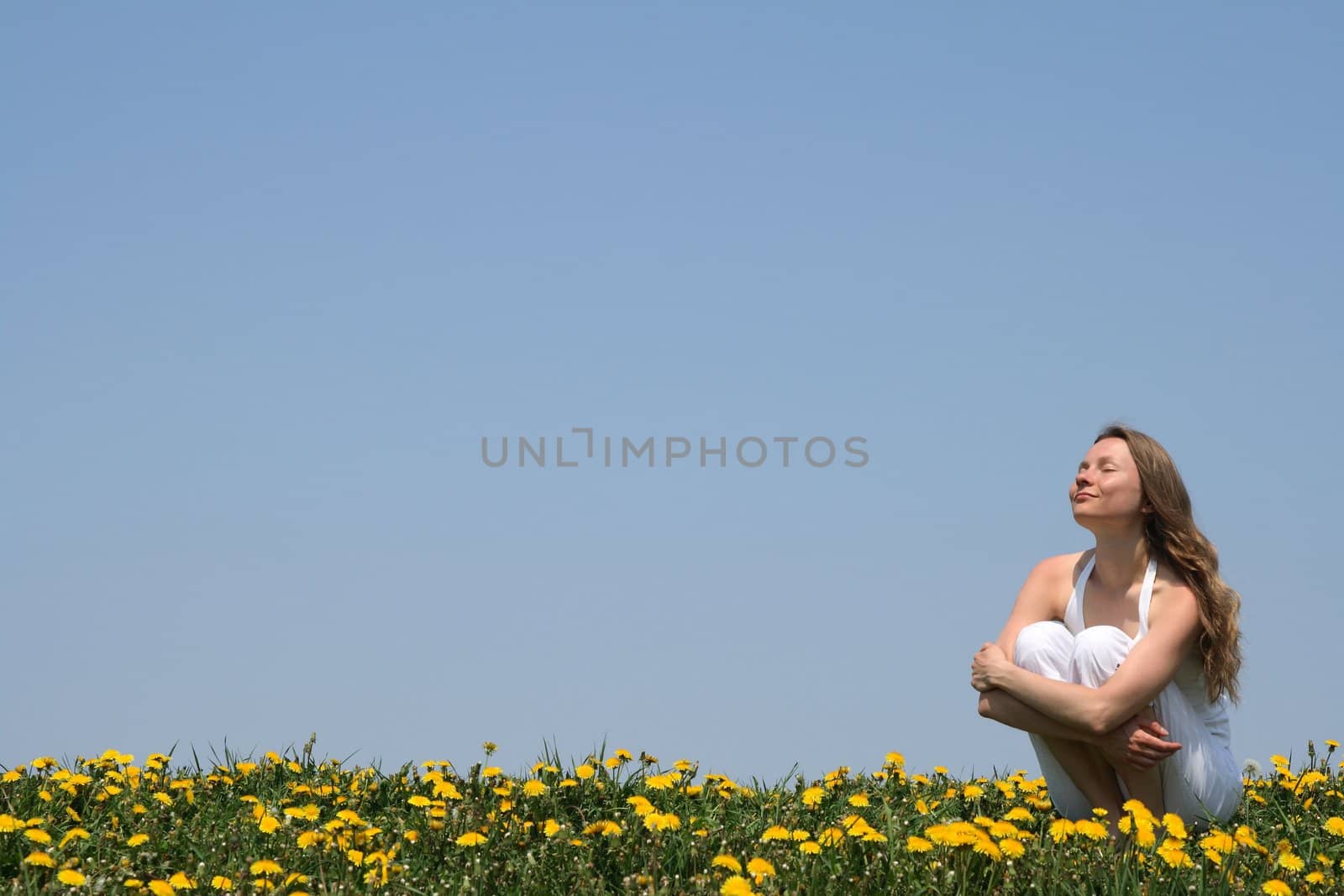 Young woman enjoying sunshine in a flowering spring field.