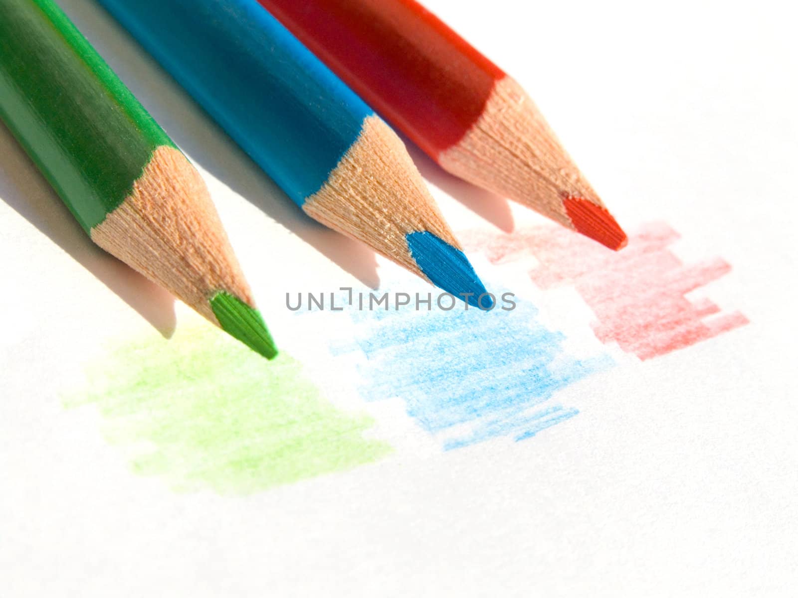 Three colored pencils on white paper sheet