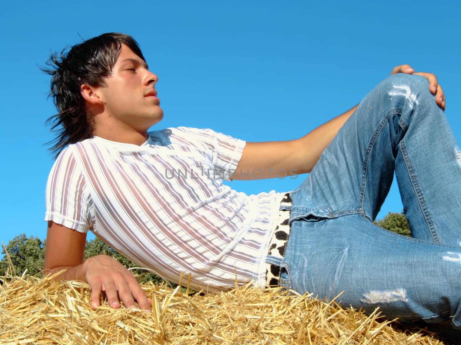 Young man lying on a hay bale in the country