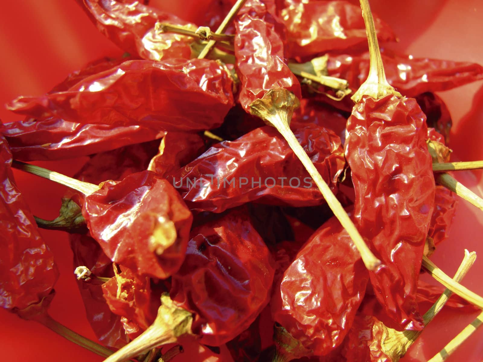 Close-up of some dried red hot chili peppers in a red plastic basket