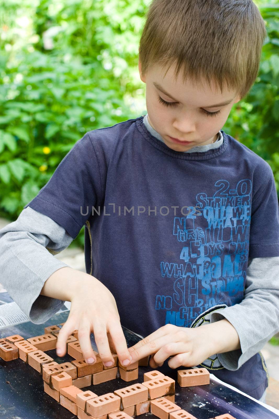 Young boy building a house with bricks
