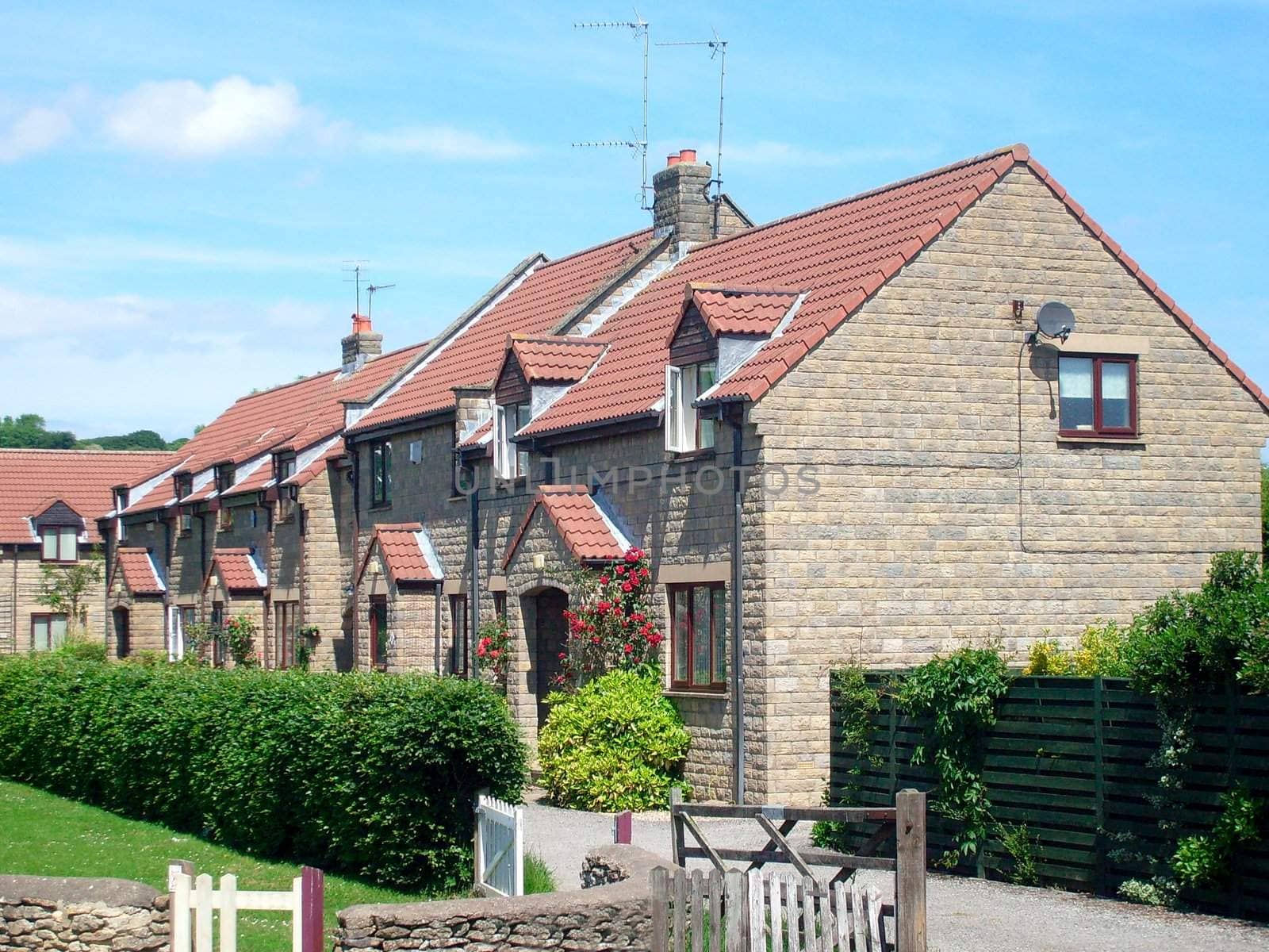 Modern English house end of terrace by village green.