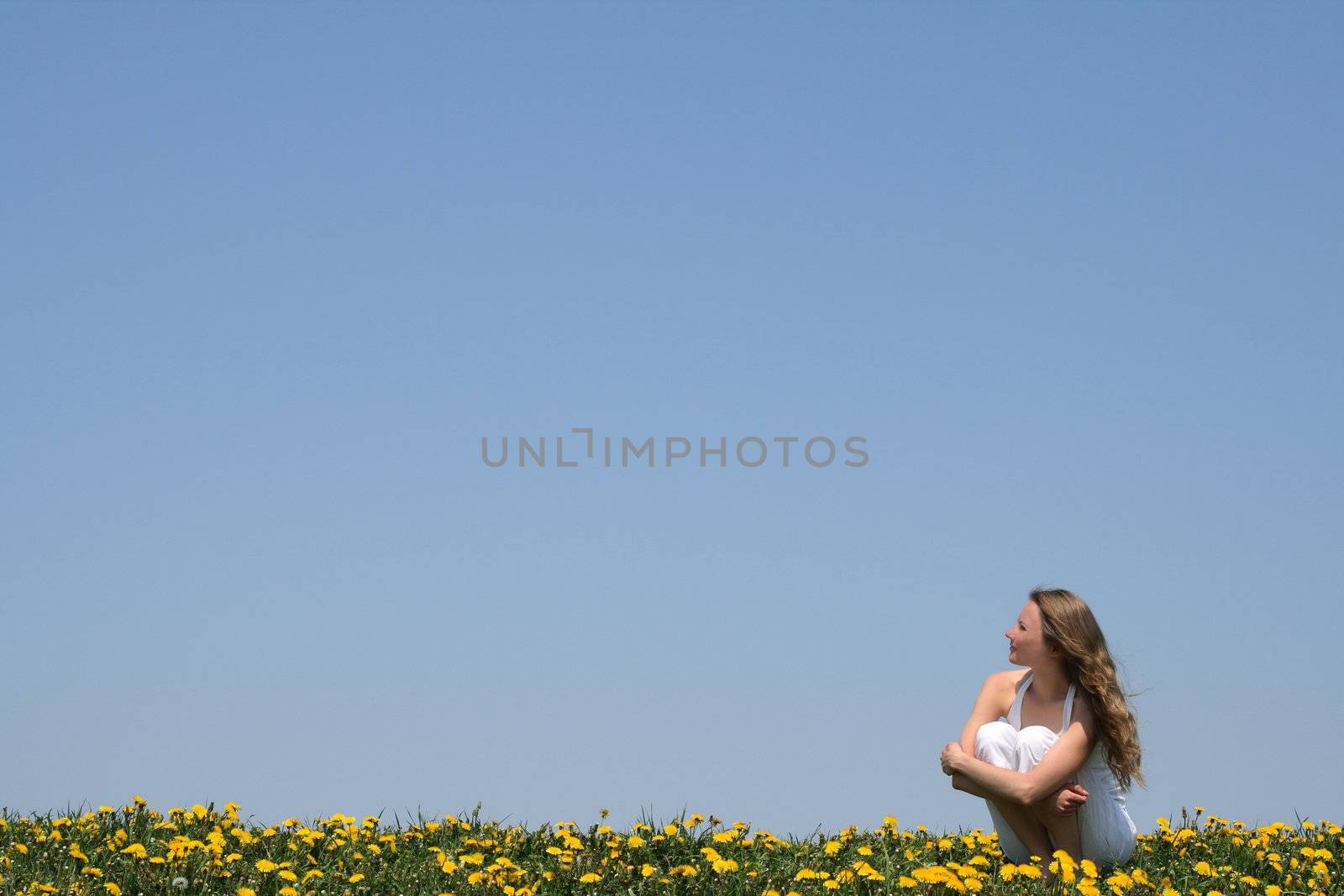 Young woman enjoying fresh air and sun in a flowering field.
