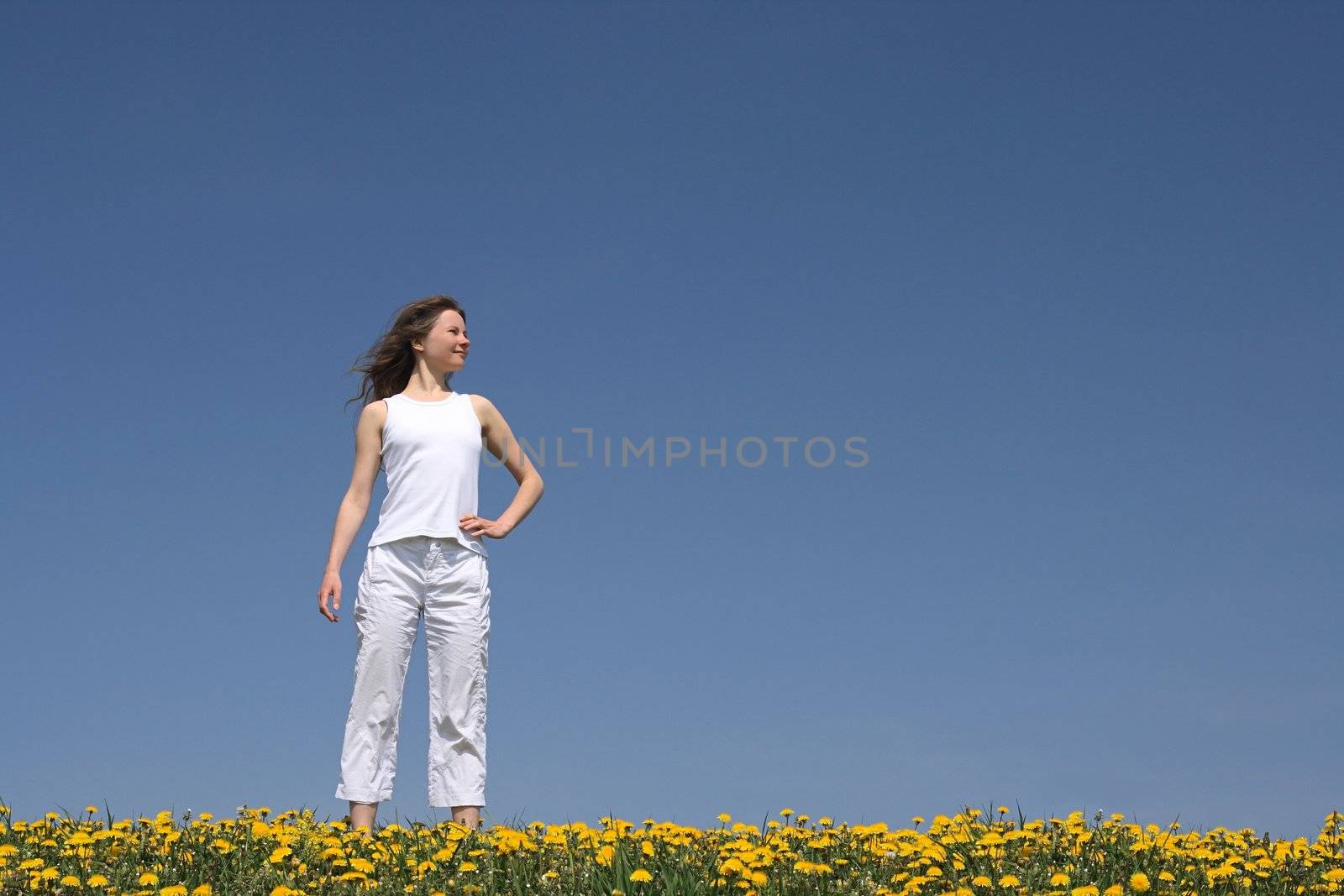 Calm young woman standing in a flowering spring field.