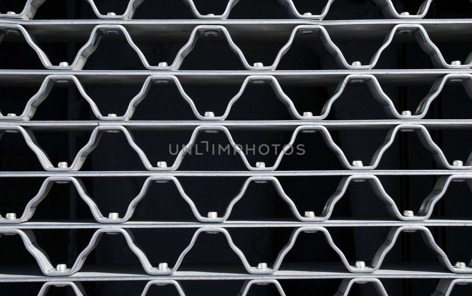 Wavy pattern of a metal grid with bolts.