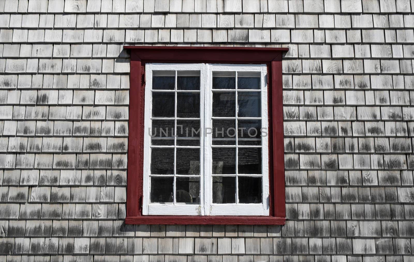 Window of an old country house with wooden tiled walls.
