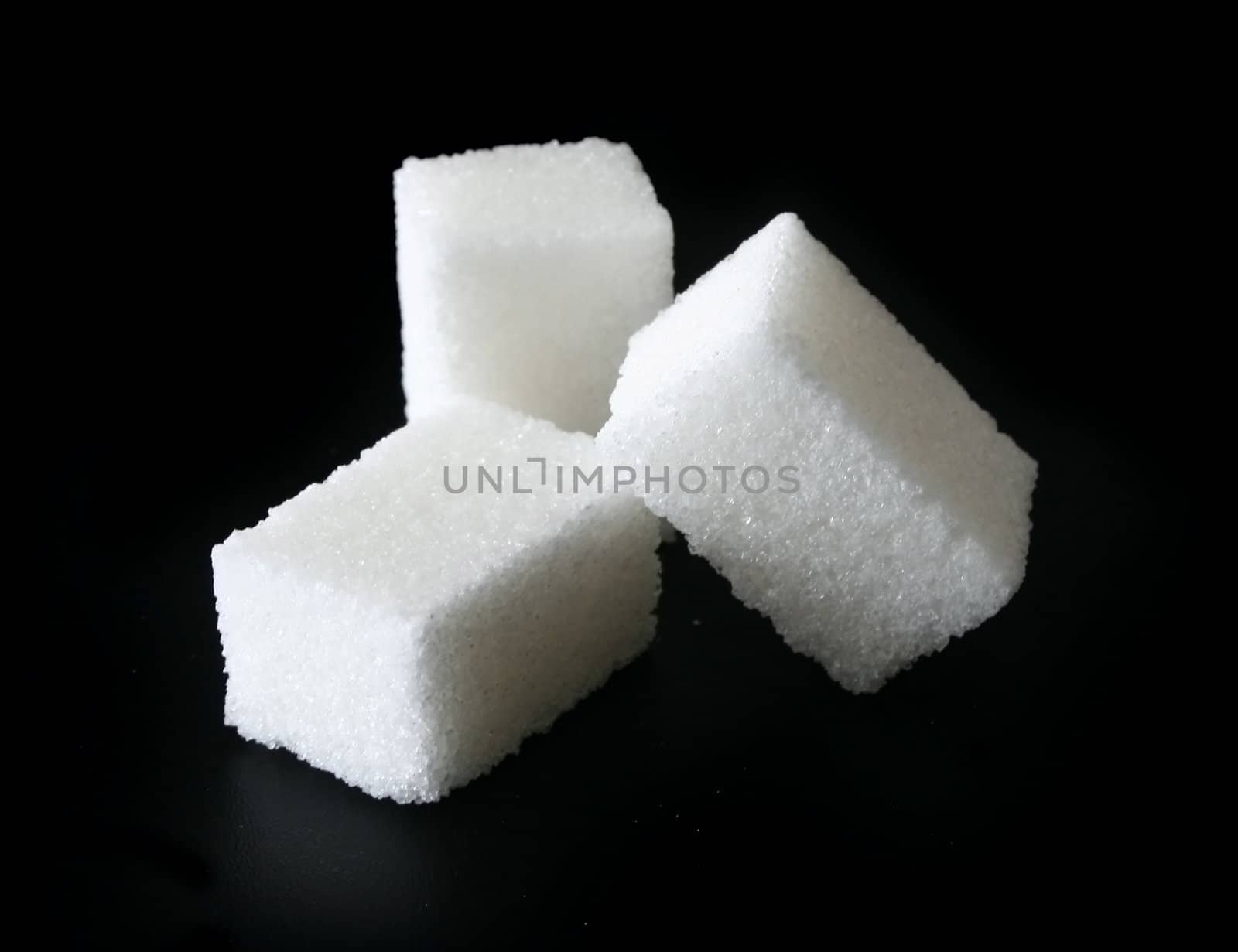 Three pieces of sugar on a black background.